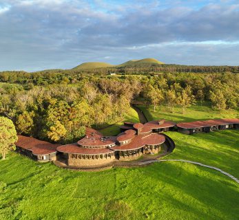 Explora Rapa Nui luxury lodge on Easter Island, featuring circular wooden architecture set amid volcanic terrain and native vegetation.