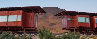 Close view of raised desert lodge with a mountain backdrop.