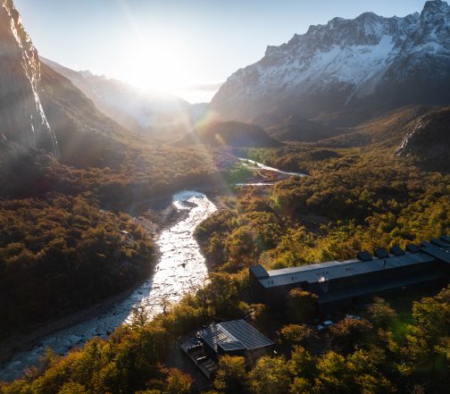 Aerial view of a luxury lodge beside a river surrounded by autumn forests in El Chaltén, Patagonia, Argentina