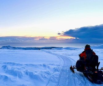 Snowmobile expedition across Vatnajökull glacier at sunset during an Iceland winter adventure