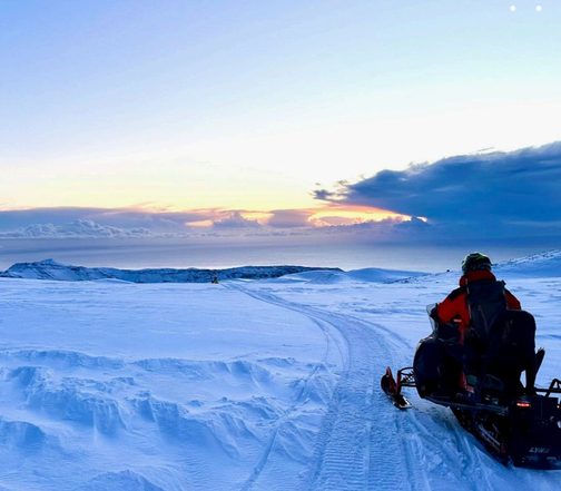 Snowmobile expedition across Vatnajökull glacier at sunset during an Iceland winter adventure